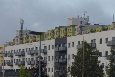 A view of contemporary multi-story residential buildings showcasing vibrant colors and balconies against a cloudy sky.