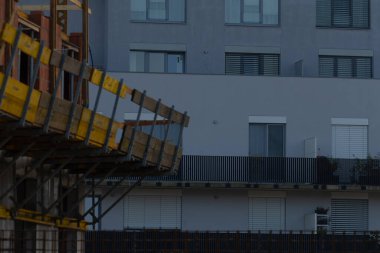 A view showcasing a construction site next to a contemporary apartment building, highlighting urban development and architectural design.