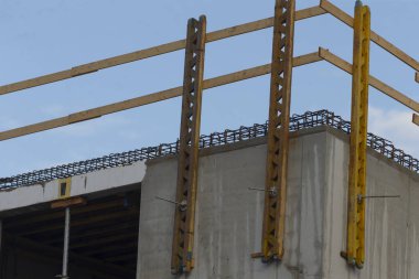 Sağlam çelik iskeleti ve berrak mavi gökyüzü altında beton yapıların yer aldığı bir inşaat sahasında modern mimari gelişmeler sergileniyor..