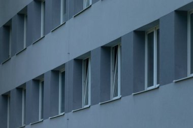 Mavi tonlu modern bir mimari stili sergileyen, sıra sıra pencereleri olan binaların soyut bir temsili..