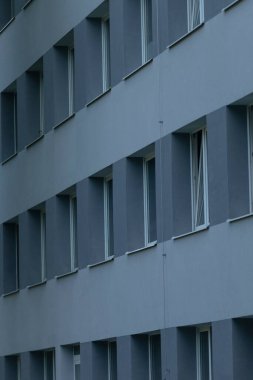 Çağdaş mimari tasarım sergilenen pencerelerin simetrik düzeninin yer aldığı modern gri bir binanın yakın plan görüntüsü.