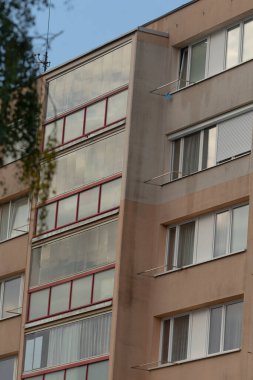 Şehir ortamında çağdaş mimariyi yansıtan, geniş pencereler ve benzersiz bir cephe tasarımı sergileyen modern bir şehir apartmanı..