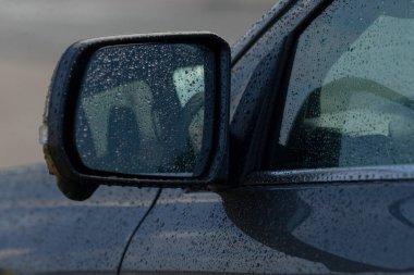 Yağmur damlalarını yansıtan, yağmurlu bir günün özünü yakalayan bir araba yan aynası. Pürüzsüz tasarım ve su damlacıkları rahatlatıcı ama dinamik bir atmosfer yaratıyor..