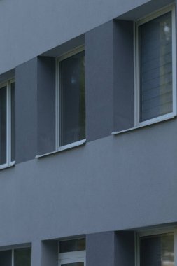 Çağdaş bir mimari tasarım sergilenen, birden fazla pencerenin yer aldığı, parlak gri bina cephesinin yakın plan görüntüsü.