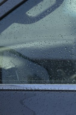 Araba camına yakın plan yağmur damlaları, sakin bir ortam ve kentsel ortamlardaki doğanın güzelliğini gösteriyor..
