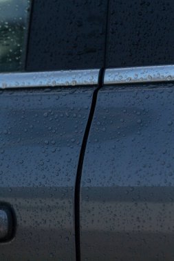 Araba kapısının yakın çekim görüntüsü yağmur damlacıkları ve kapı panelleri arasında belirgin bir boşluk, potansiyel hizalama sorunlarını vurguluyor.