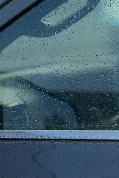 Araba camına yakın plan yağmur damlaları, sakin bir ortam ve kentsel ortamlardaki doğanın güzelliğini gösteriyor..