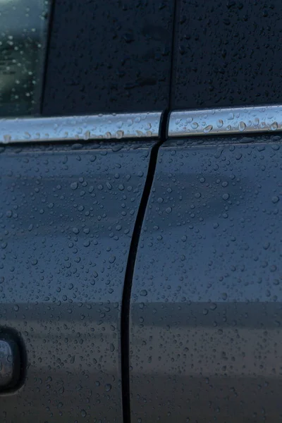 Araba kapısının yakın çekim görüntüsü yağmur damlacıkları ve kapı panelleri arasında belirgin bir boşluk, potansiyel hizalama sorunlarını vurguluyor.