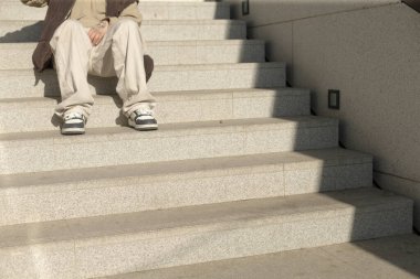 A person is sitting comfortably on a set of sturdy stairs, with the number 10 clearly displayed on the wall right behind them, enhancing the scene