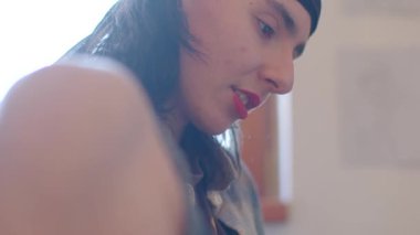 The video showcases a tattooed person writing, with closeups of a woman in a hat and another in a bandana, adding emotional depth