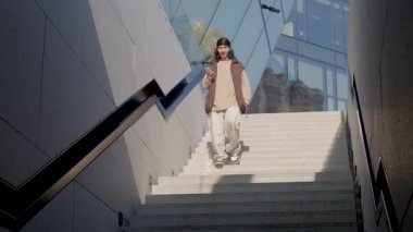 The video shows people interacting with a staircase a man goes up, a woman goes down on her phone, and another man is at the top, focused on his phone, ending with a woman observing the area