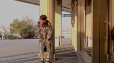 A man in a plaid shirt dances with another by a vibrant sign. Scenes shift to a parking lot, a thoughtful boy on a bench, and then confidently on a sidewalk