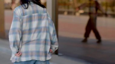 A short film captures urban life, featuring a man and woman walking a bustling sidewalk. The scene shifts to an individual sitting on the ground, reflecting