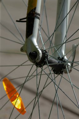 Mekanik ve güvenlik yansıtıcısını gösteren bisiklet çatalı ve tellerin ayrıntılı görüntüsü.