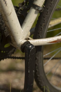 Dağ bisikletlerinin krank, pedal ve zincirinin detaylı görüntüsü, toprak ve giysi sergileniyor. Bisiklet meraklıları ve motor bakım içeriği için ideal.