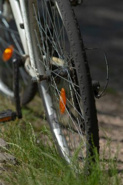 Yeşilli, yemyeşil bir zemin üzerine kurulmuş, lastik ve tellerin detaylarını gösteren bir bisiklet tekerleğinin yakın plan görüntüsü. Açık hava ve bisiklet temalı projeler için mükemmel.