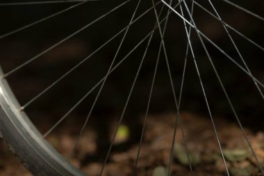 Bulanık doğal bir arka plan üzerine kurulmuş bisiklet tekerleği tellerinin detaylı yakın plan çekimi. Bisiklet ve açık hava temaları için mükemmel.