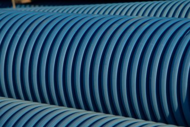 Endüstriyel bir ortamda düzgünce istiflenmiş mavi ve ahenkli boruların yakın plan görüntüsü, dokusunu ve rengini vurguluyor..