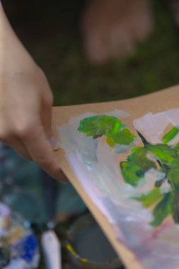 A skilled person is focused on painting a detailed picture of a vibrant plant on a clean piece of paper with various colors