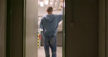 A sequence of a young man joyfully dancing in an industrial space, showcasing carefree movements and energetic vibes.