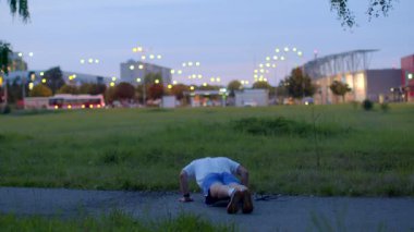 This video features a man committed to a nighttime fitness routine in a peaceful park, running, stretching, and doing pushups, showcasing perseverance