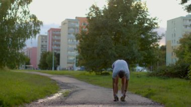 A man performs an energetic workout in a scenic park, jumping rope and stretching his legs, highlighting the joy of outdoor exercise and nature