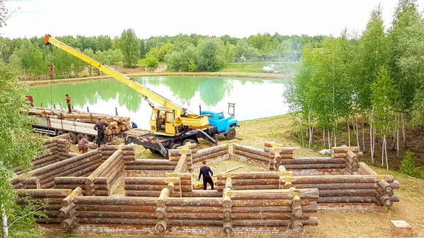 Bir kütükten ev inşa etmek. Bir grup adam bir vakfa kütük ev kuruyor..