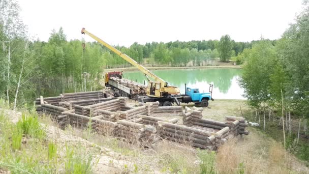 Construyendo una casa desde un tronco. Un grupo de hombres instalan una casa de madera sobre una base. — Vídeos de Stock