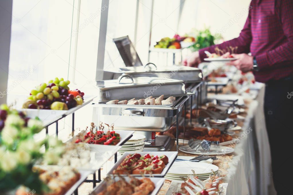 Beautifully decorated catering banquet table with variety of different food snacks and appetizers on corporate christmas birthday party event or wedding celebratio