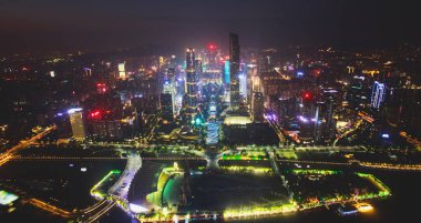 Beautiful wide-angle night aerial view of Guangzhou Zhujiang New Town financial district, Guangdong, China with skyline and scenery beyond the city, seen from the observation deck of Canton Tower clipart