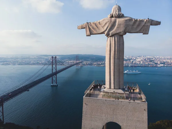 View of The Sanctuary of Christ the King, Cristo Rei, Almada, Lisbon, with 25 de Abril Bridge suspension Bridge, Tagus river, aerial drone view in summer sunny da