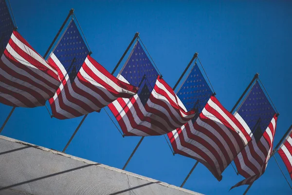 View of waving American flag in the wind with beautiful blue sky in background, line of United States of America Flag