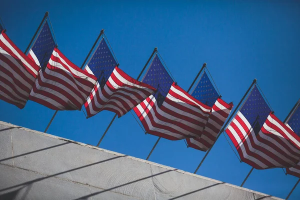 View of waving American flag in the wind with beautiful blue sky in background, line of United States of America Flag
