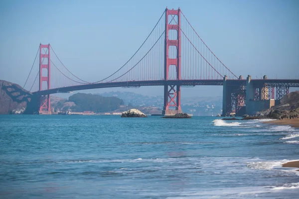 Classic panoramic view of famous Golden Gate Bridge seen from Baker Beach in beautiful summer sunny day with blue sky, San Francisco, California, US