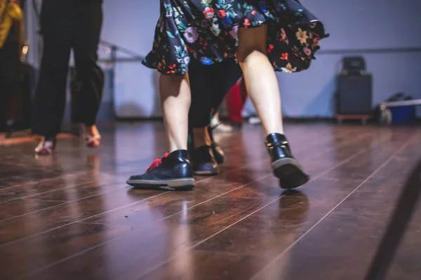 Dancing shoes of young couple dance retro jazz swing dances on a ballroom club wooden floor, close up view of shoes, female and male, dance lessons