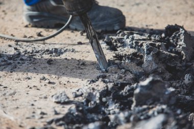 Yol onarımı, matkap, pnömatik çekiç ve matkap ile inşaat işçisi inşaat alanında asfalt kaldırım ve beton kırma ekipmanları ile çalışır.