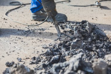 Yol onarımı, matkap, pnömatik çekiç ve matkap ile inşaat işçisi inşaat alanında asfalt kaldırım ve beton kırma ekipmanları ile çalışır.