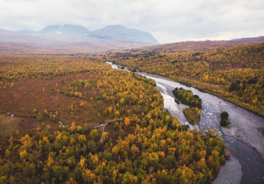 Aerial sunny fall autumn view of Abisko National Park, Kiruna Municipality, Lapland, Norrbotten County, Sweden, shot from drone, with Abiskojokk river, road and Nuolja mountai clipart