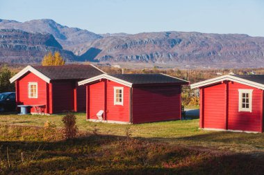 Geleneksel ahşap kırmızı kulübeleriyle klasik Norveç kamp alanı manzarası, Kuzey Norwa