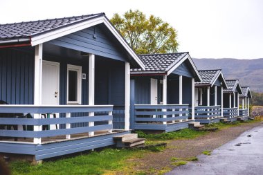 Geleneksel ahşap kırmızı kulübeleriyle klasik Norveç kamp alanı manzarası, Kuzey Norwa