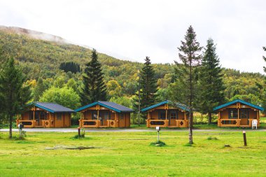Geleneksel ahşap kırmızı kulübeleriyle klasik Norveç kamp alanı manzarası, Kuzey Norwa
