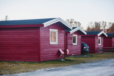 Geleneksel ahşap kırmızı kulübeleriyle klasik Norveç kamp alanı manzarası, Kuzey Norwa