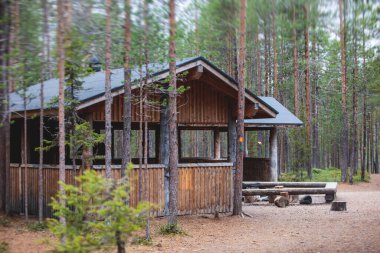 Finnish Ulusal Parkı manzarası: Ahşap kulübe, kulübe kulübesi, ahşap asma köprü, ahşap merdiven basamakları, kamp alanı, masa, ateş çukuru, bank ve Oulanka, Lapland, Finlandiya