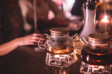 Masada mumlar ve dumanla Nargile manzarası arka planda sigara içen gençlerle nargile salonu, Shisha parti kulübü konsepti.