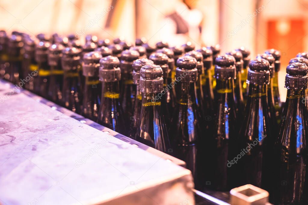 View of glass bottles on the conveyor belt, bottle necks on the production line, brewery equipment, inside wine factory, process of alcohol liquor manufacture production