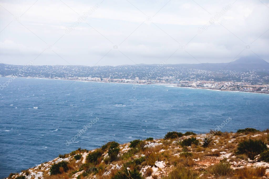 Beautiful super wide-angle aerial view of Xabia, Javea, Marina Alta with harbor and skyline, mountains, beach and city, seen from Cabo de San Antonio viewpoint, province of Alicante, Valencia, Spai