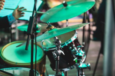 Davulcu perküsyonist, caz rock gösterisi sırasında davul setiyle sahnede performans sergiliyor, arka planda orkestra performansı, davulcu, arka planda ise davulcu.