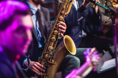 Sahnede caz orkestrası çalarken saksafoncu, saksafoncu, vokalist ve müzikalistin konser görüntüsü