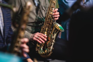Sahnede caz orkestrası çalarken saksafoncu, saksafoncu, vokalist ve müzikalistin konser görüntüsü