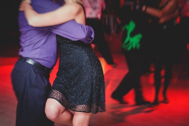 Couples dancing argentinian dance milonga in the ballroom, tango lesson in the red lights, dance festival clipart